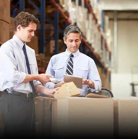 Two men in a warehouse looking at papers.