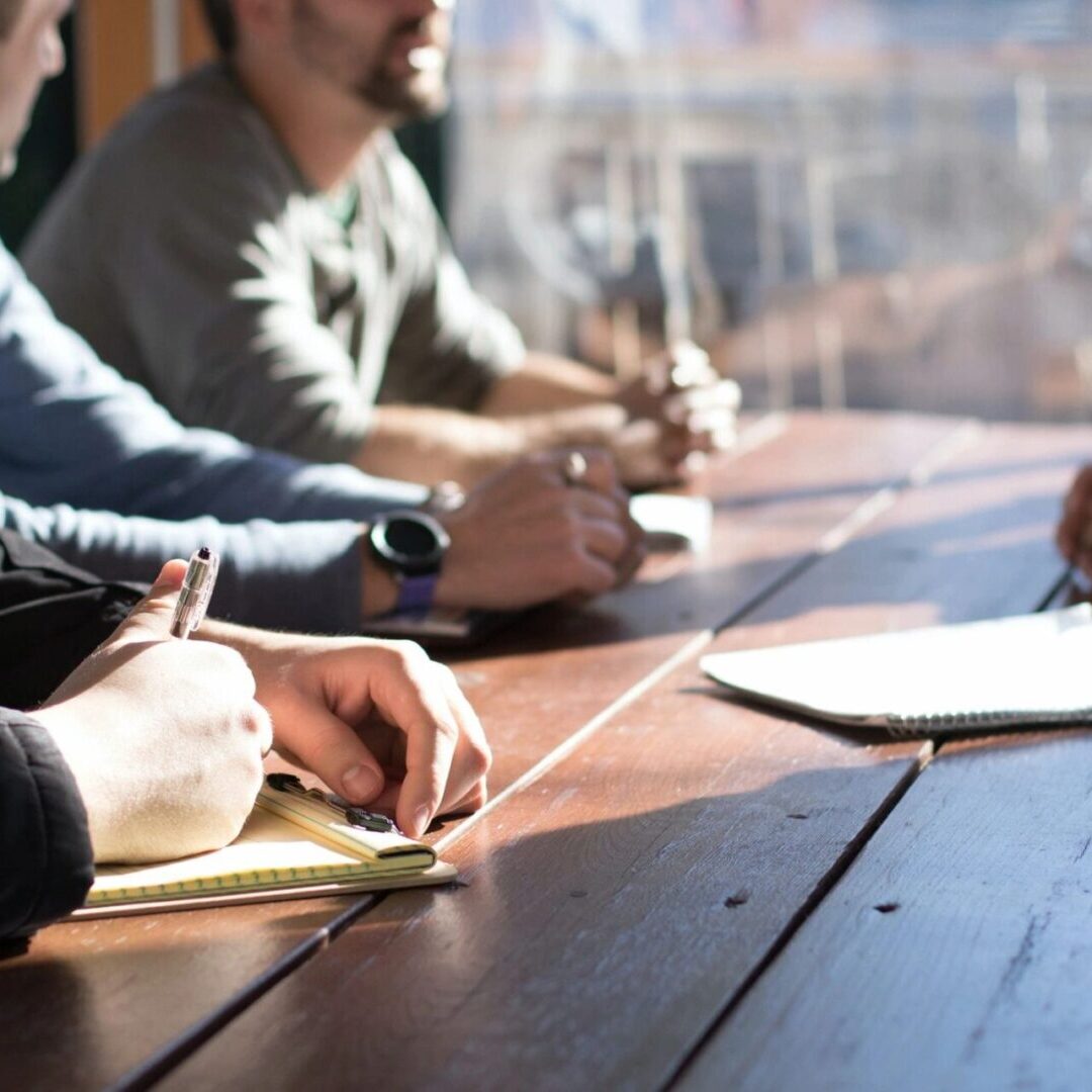 A group of people sitting at a table writing on paper.